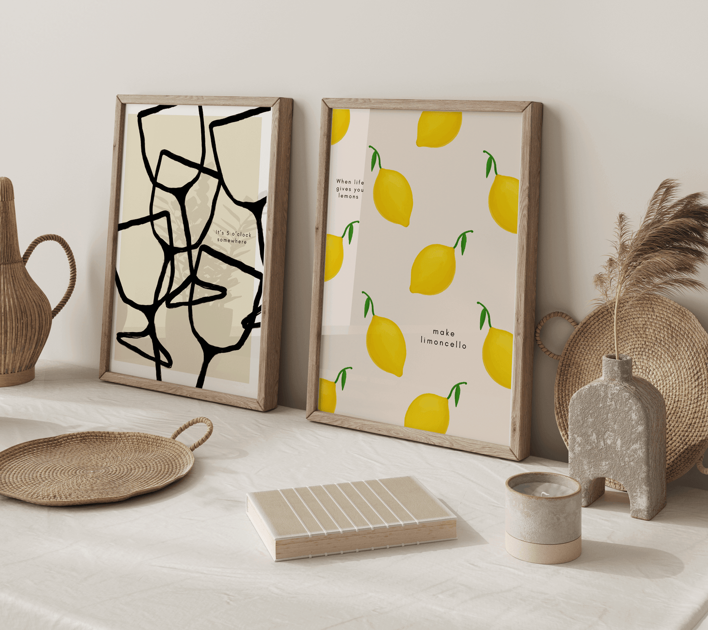 Two prints on a kitchen counter, one displaying lemons with the words "when life gives you lemons, make limoncello" alongside a monochrome print featuring abstract wine glasses with the caption "it's 5 o'clock somewhere"