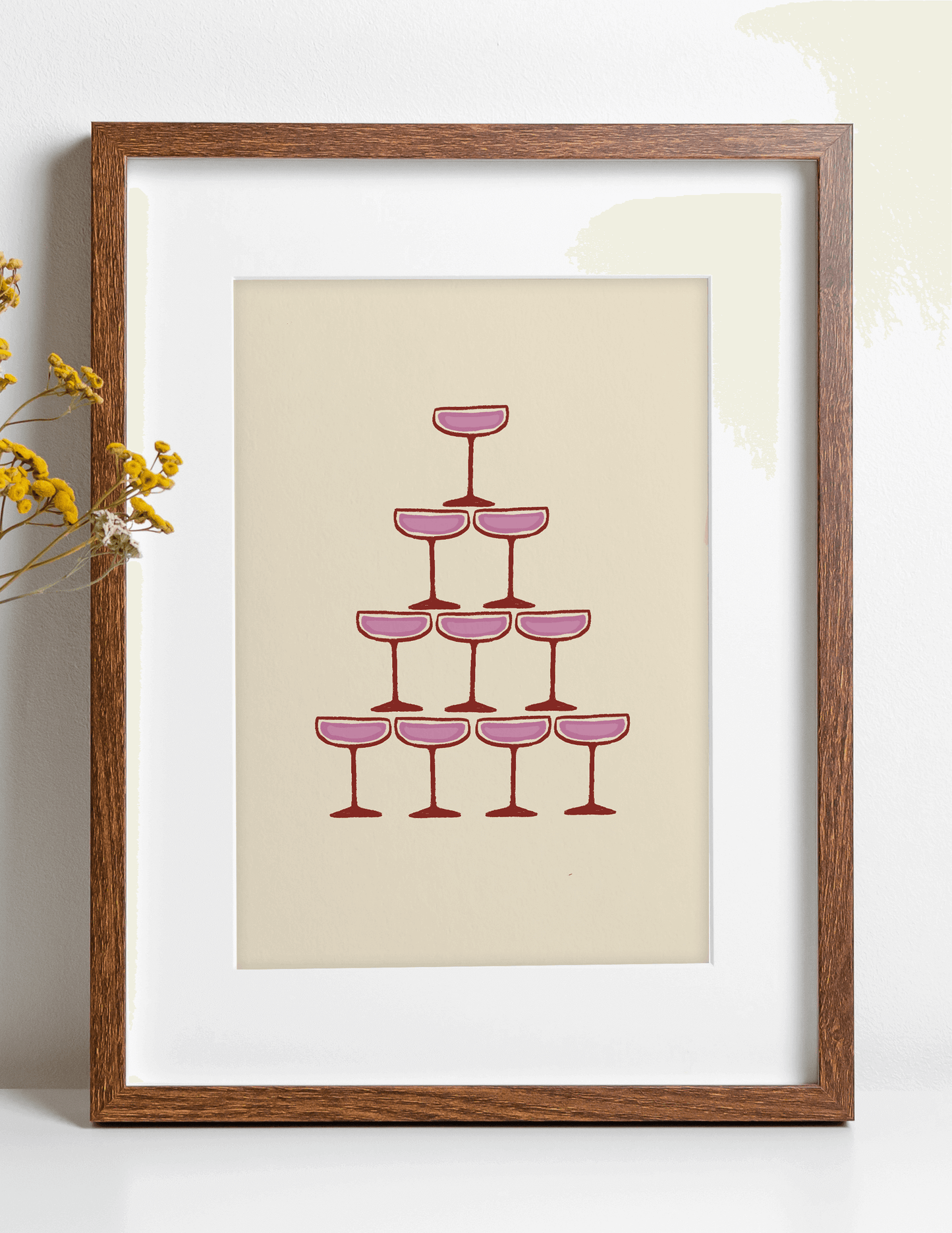 Pink illustration of champagne coupe's forming a champagne fountain, framed, leaning against a wall on a kitchen counter