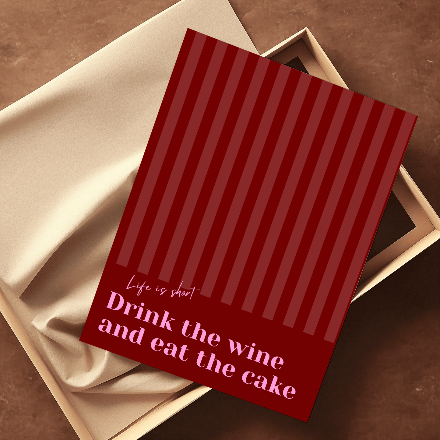 Red and pink typography print, unframed laying on parchment paper featuring the quote "Life is short. Drink the wine and eat the cake"