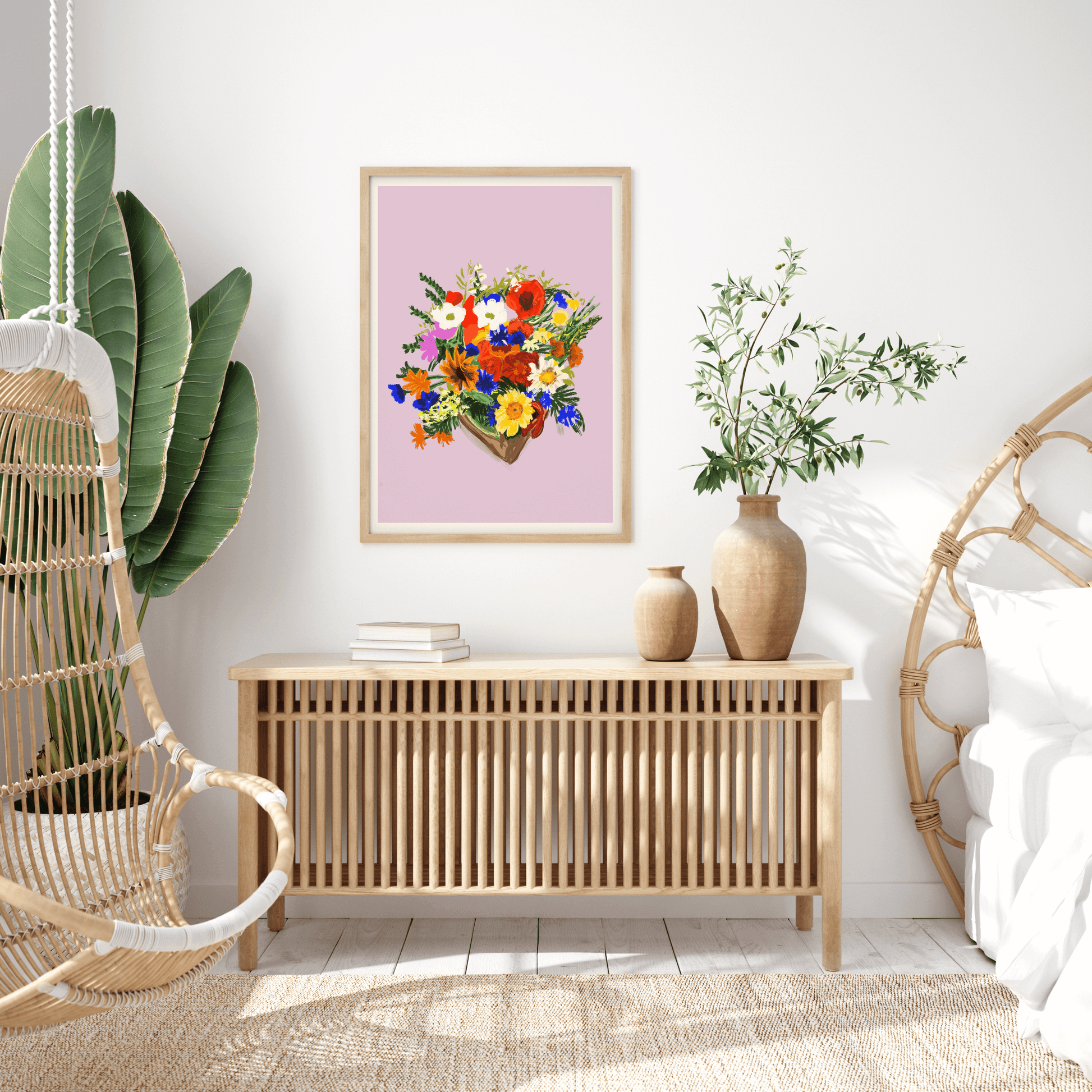 Print features a bouquet of colourful bouquet of flowers, against a dusty pink/lilac background with a small white border. The bouquet features yellows, blues, reds, whites and green foliage. Print is displayed in a wall-hung frame surrounded by boho, sca