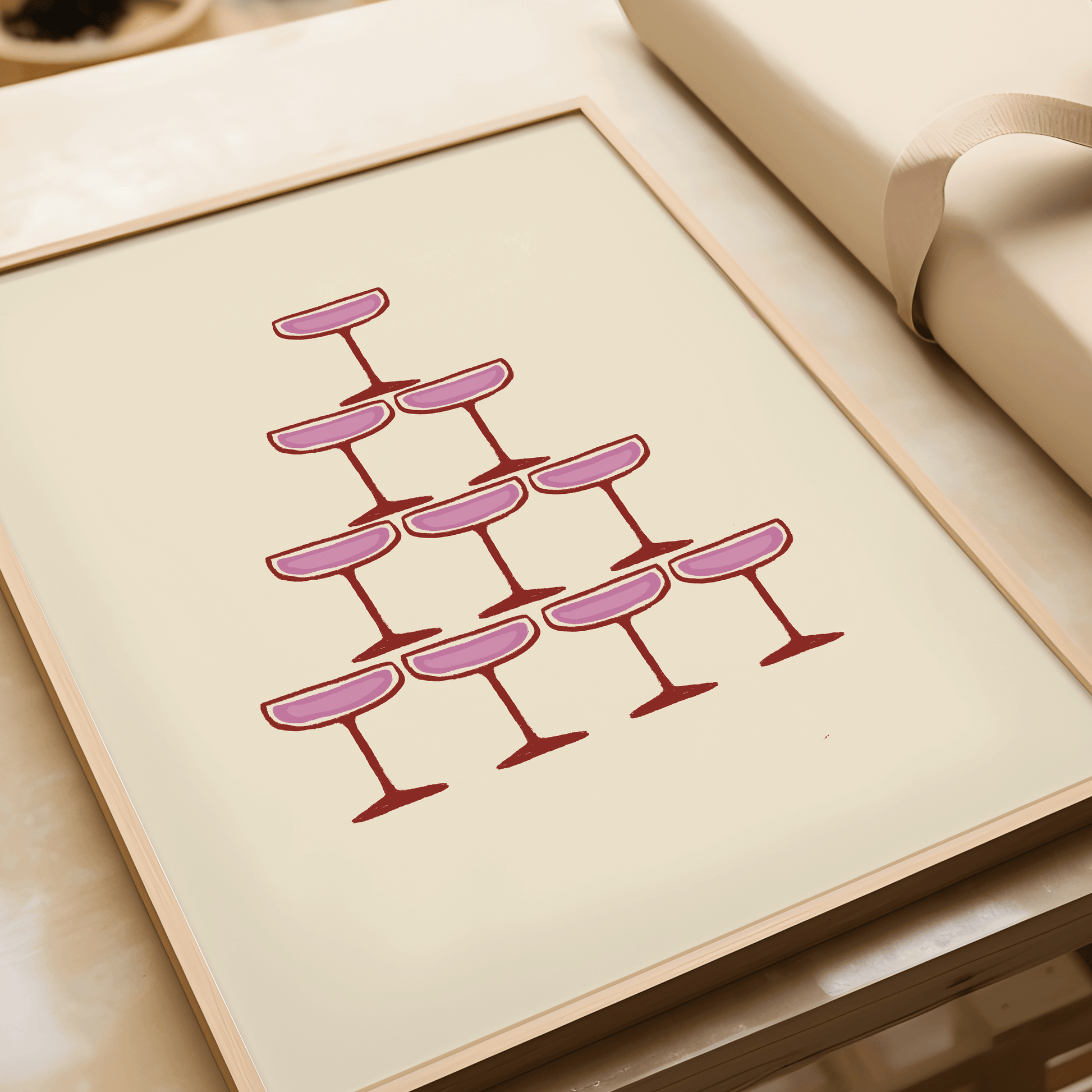 Pink illustration of champagne coupe's forming a champagne fountain, framed, laying flat on a table